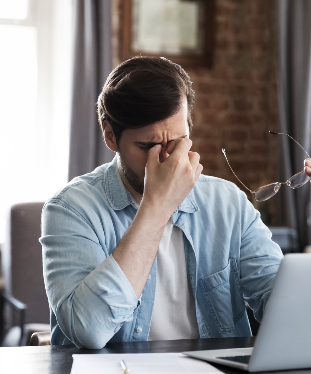 Gestresster Mitarbeiter sitzt erschöpft am Schreibtisch und reibt sich die Augen – Symbolbild für Überlastung, fehlende Anerkennung und nachlassende Motivation im Arbeitsalltag.